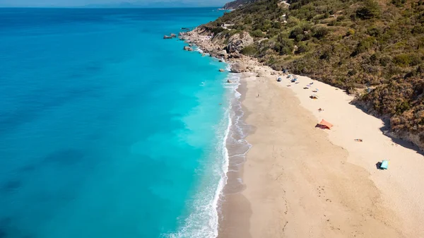 Güneş gözlüklü ve yumuşak turkuaz okyanus dalgalı güzel kumlu sahil manzarası. Yaz mevsiminde Lefkada adasındaki Megali Petra plajında tropikal deniz.
