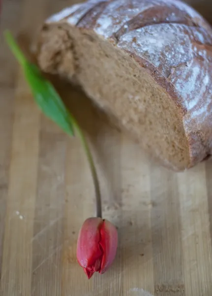 Meio pão escuro e flor vermelha — Fotografia de Stock