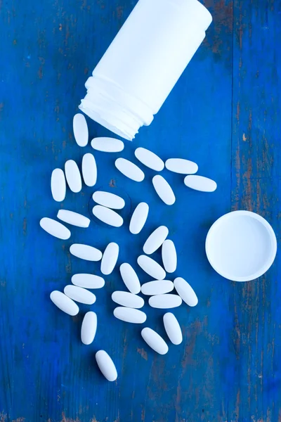 Oblong medicine tablet white spill on the blue board — Stock Photo, Image