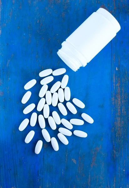 Oblong white medicine tablet on the blue board — Stock Photo, Image