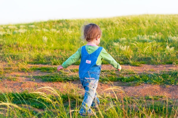 Kind in de jeans coverall lopen met krachtige stappen — Stockfoto