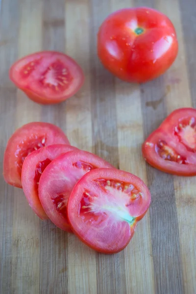 Резьба и целые помидоры на доске — стоковое фото