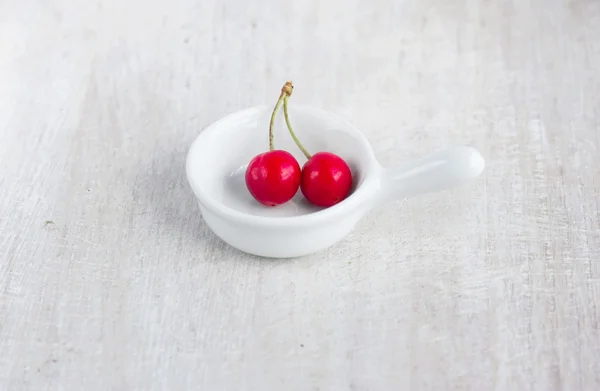 Two red berry - sweet cherry in the white gravy boat — Stock Photo, Image