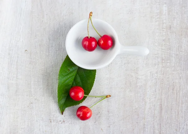 Red berry - sweet cherry in the white gravy boat and green leaf — Stock Photo, Image