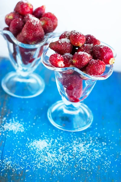 Sweet juicy strawberry with sugar in the glass beaker on the blu — Stock Photo, Image