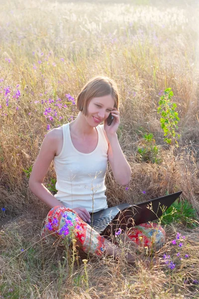 Hermosa mujer positiva con portátil y teléfono móvil — Foto de Stock