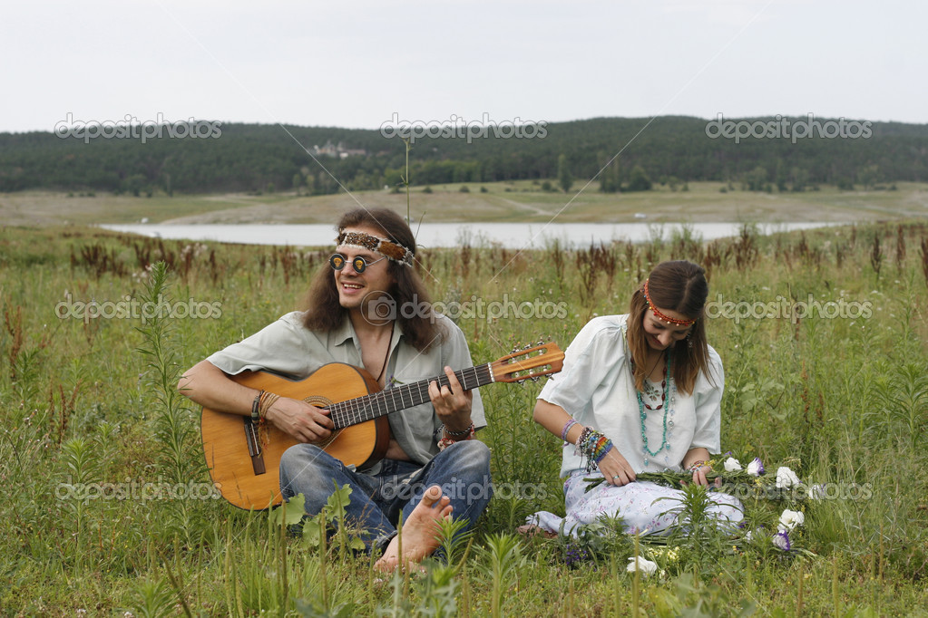 hippie men play on the guitar and woman make a wreath