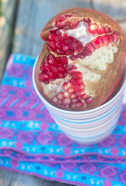 Pomegranate in the cup on the patterned material — Stock Photo, Image