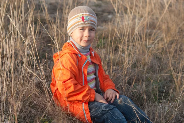 Kleine jongen in het droog gras — Stockfoto