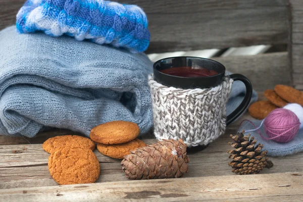 Can with hot beverage and knitting clothes — Stock Photo, Image