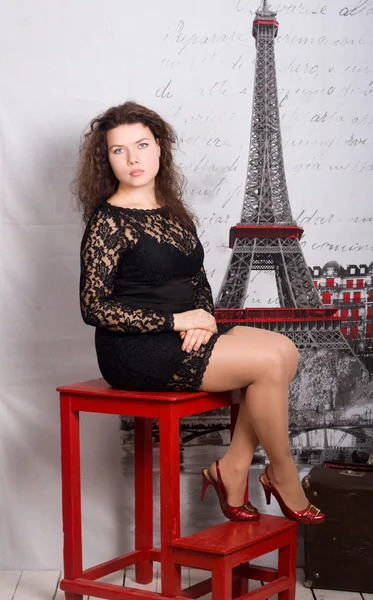 Curly-haired young woman on a red chair — Stock Photo, Image