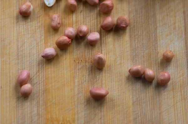 Spilled raw peanuts on the wooden board — Stock Photo, Image