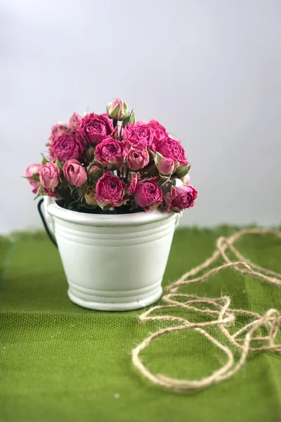 Pink roses in a decorative bucket on a green background — Stock Photo, Image