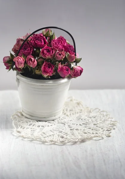 Rosas en un cubo pequeño decorativo en una servilleta de encaje — Foto de Stock