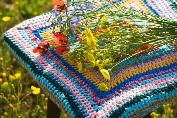 Bouquet of wild flowers on a striped cover for stool to crochet — Stock Photo, Image