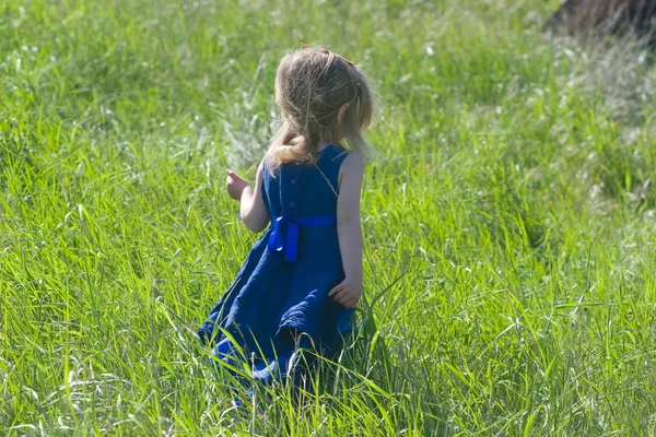 Little girl in a blue dress running away — Stock Photo, Image