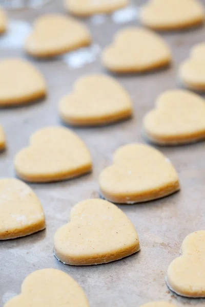 Biscotti crudi a forma di cuore frolla sulla teglia, selectiv — Foto Stock