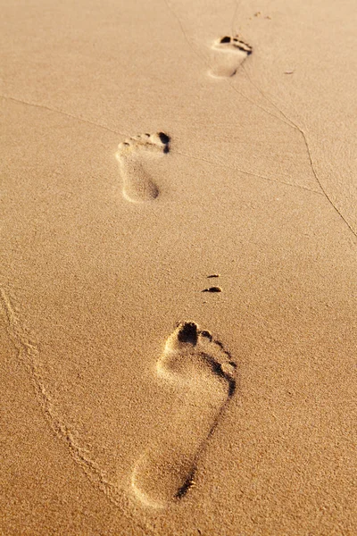 Drie menselijke voetafdrukken op het strand zand — Stockfoto