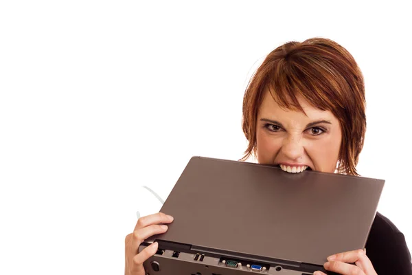 Frustrated Caucasian businesswoman biting laptop — Stock Photo, Image