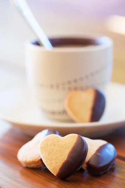 Chocolate dipped heart shaped cookies and cup of coffee — Stock Photo, Image