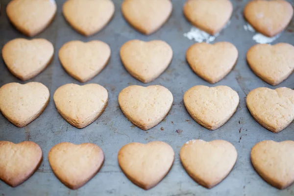 Las filas horizontales de corazón dan forma a las galletas en la bandeja para hornear —  Fotos de Stock