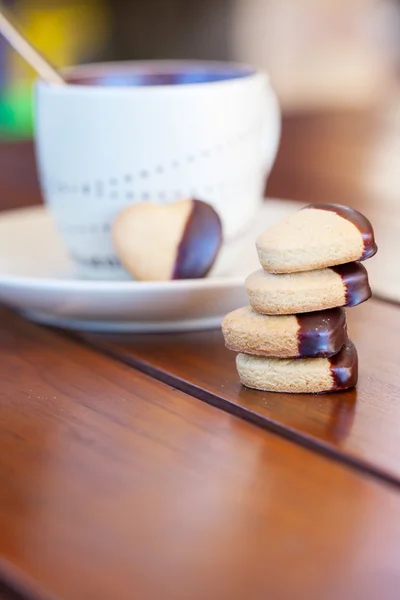 Stacked chocolate dipped heart shaped cookies and cup of coffee — Stock Photo, Image