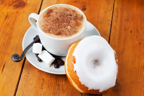 Fresh cappuccino and doughnut with white frosting — Stock Photo, Image