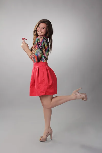 Ein hübsches Mädchen in einem roten Kleid mit Beeren in der Hand. Foto in voller Länge — Stockfoto