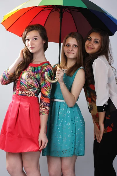 Drei schöne Mädchen unter einem Regenschirm. . — Stockfoto