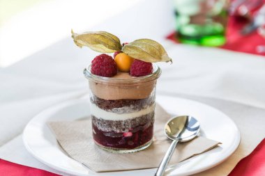 Ahududu ve bitki örtüsüyle süslenmiş bardakta mini kara orman keki.