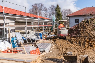 Küçük bir kazıcıyla ev ve toprak inşaatı yapılırken inşaat alanı