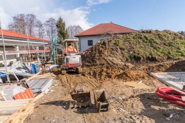 İnşaat makinası bir inşaat sahasında ev inşa ederken mini kazıcı