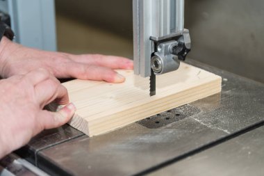 Marangoz ahşap atölyesinde testereyle odun testeresi kesiyor.