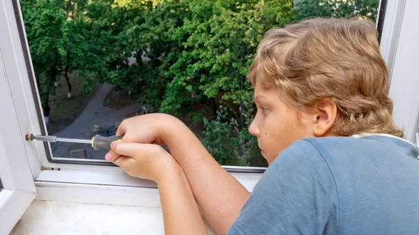 Ein Junge mit einem Schraubenzieher hilft, die Schraube anzuziehen Stockbild