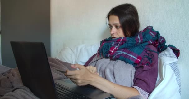프리랜서 여성 이 노트북 과 태블릿을 사용하여 추위에 떨고 있는 동안 집에서 일하는 모습 — 비디오