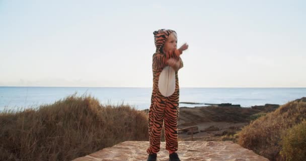 Lindos niños en un traje de tigre en el amanecer soleado junto al mar haciendo ejercicios deportivos — Vídeos de Stock