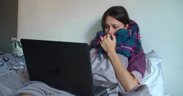 Ziekte vrouw in sjaal in quarantaine werken van thuis uit op het bed op haar laptop — Stockvideo
