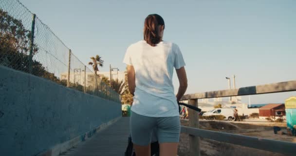Vista posteriore della donna che cammina in argine con passeggino per bambini in vacanza estiva — Video Stock