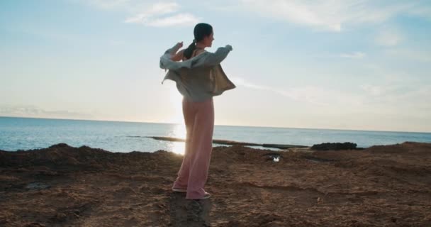 Ung glad smal vacker kvinna dansar och hoppar på stenar på soluppgången — Stockvideo
