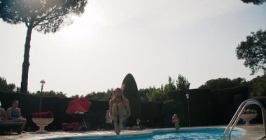 Genç adam yaz tatillerinde yüzme havuzuna atlıyor.