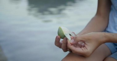 Genç kadın elleri, arka planda su olan incir meyvelerini soyar.