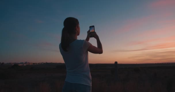 Giovane donna attraente riprese bel tramonto con il suo smartphone all'aperto — Video Stock
