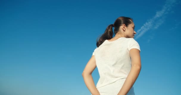 Молодая взрослая привлекательная женщина смотрит вокруг на голубое небо в качестве фона — стоковое видео