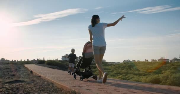 Familj promenader tillsammans utomhus på kvällen mamma och barn på solnedgången — Stockvideo