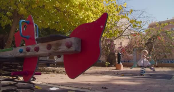 Balançoire printanière solitaire sur une aire de jeux pour enfants dans un parc public, enfant déconcentré — Video