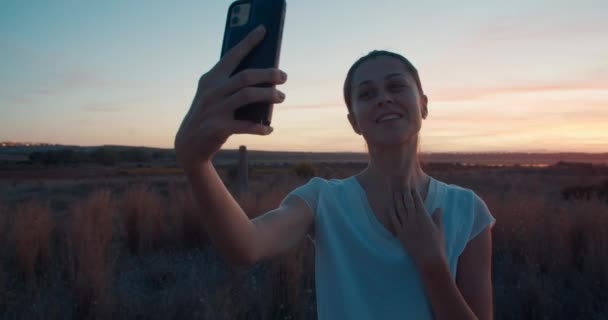 Vooraanzicht van mooie brunette vrouw maken selfie op kleurrijke zonsondergang — Stockvideo