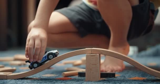 Les mains de l'enfant se rapprochent en jouant avec la voiture jouet sur le chemin de fer en bois — Video