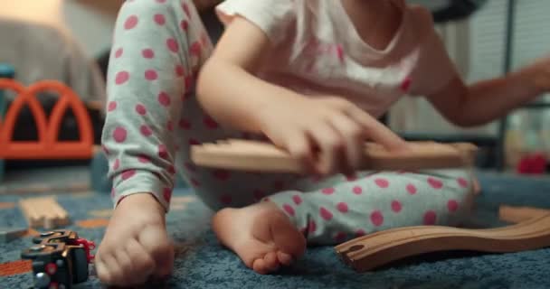 Baby flicka montering trä järnväg väg i vardagsrummet på kvällen i hemmet — Stockvideo