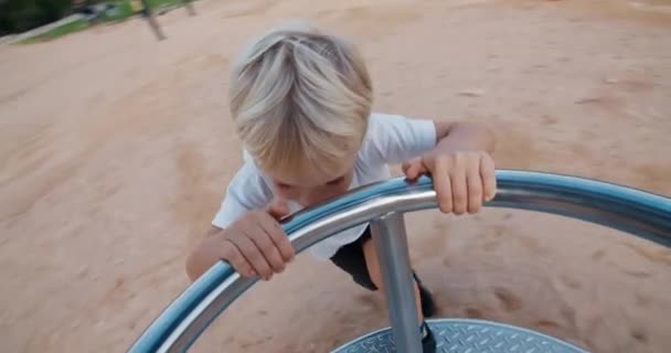 Szczęśliwe dziecko na placu zabaw wirujące na huśtawce karuzeli i śmiejące się na zachodzie słońca — Wideo stockowe