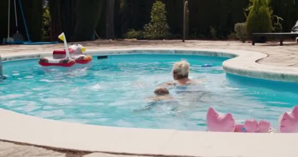 Детское плавание с бабушкой в бассейне на летних каникулах в Испании — стоковое видео